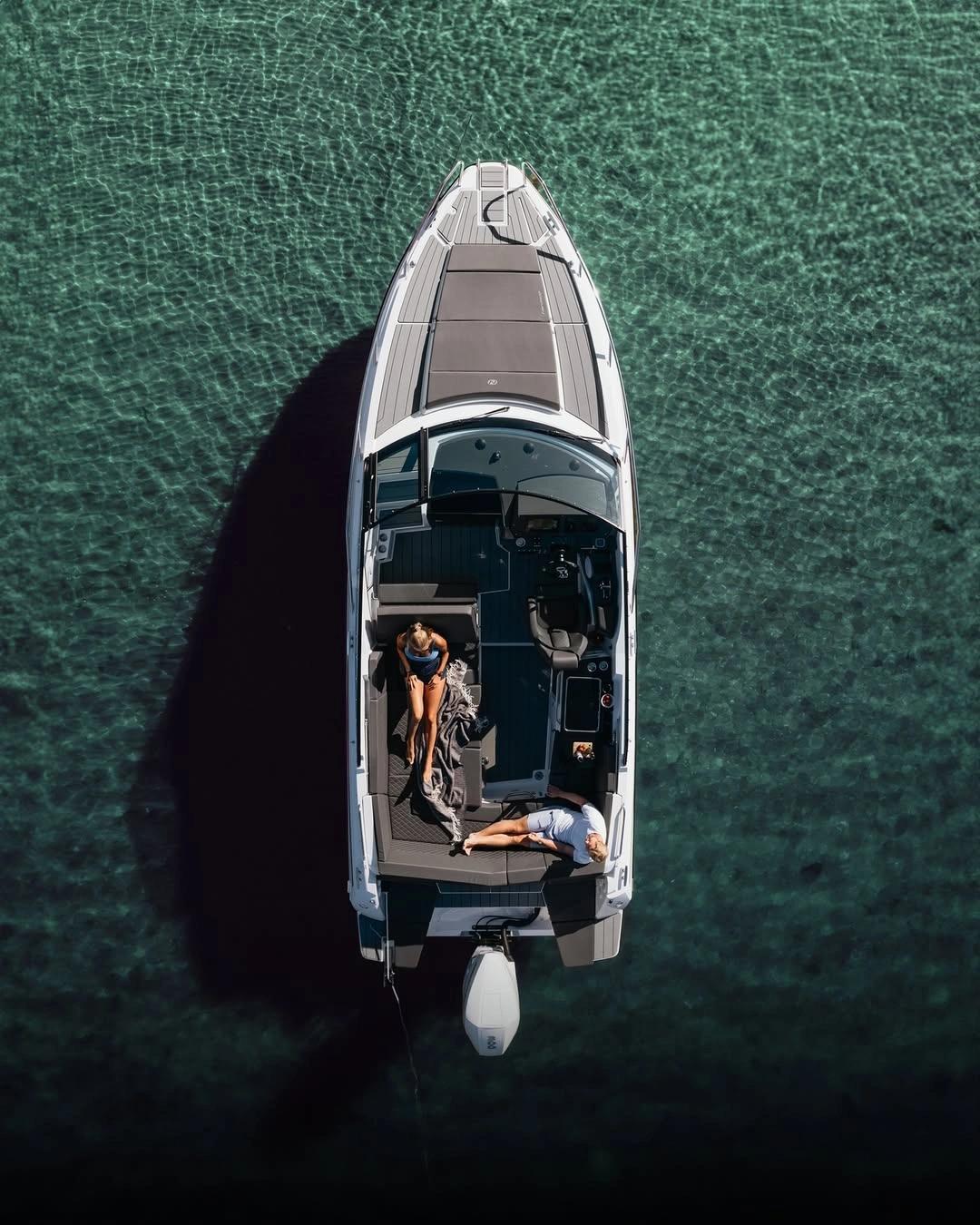 Vue aérienne d'un bateau de luxe blanc amarré en mer turquoise avec deux personnes à bord, Contact Nautimarine