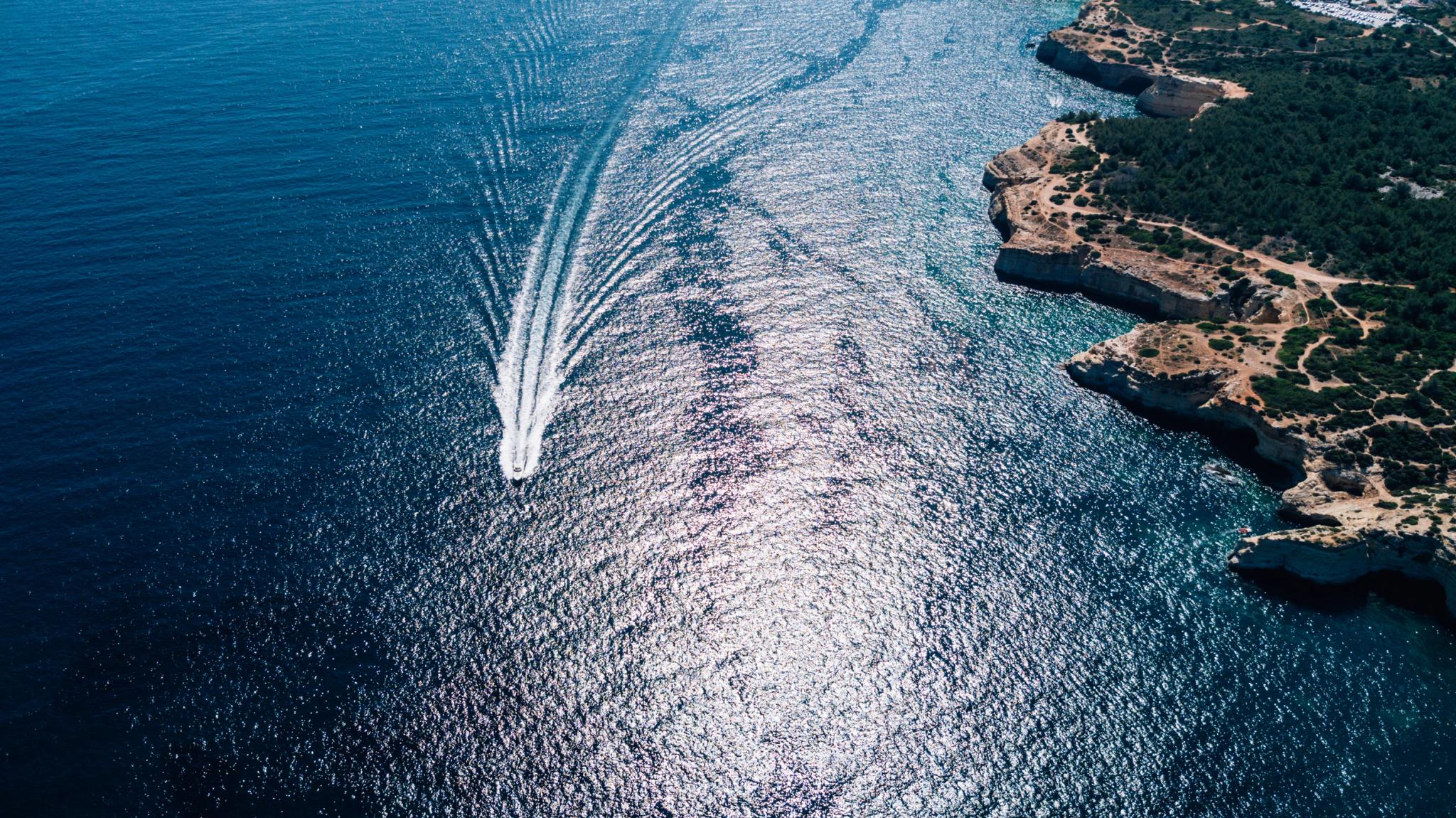 Bateau créant des vagues en mer près des falaises rocheuses de l'Île-Rousse en Balagne pour l'entretien de bateau