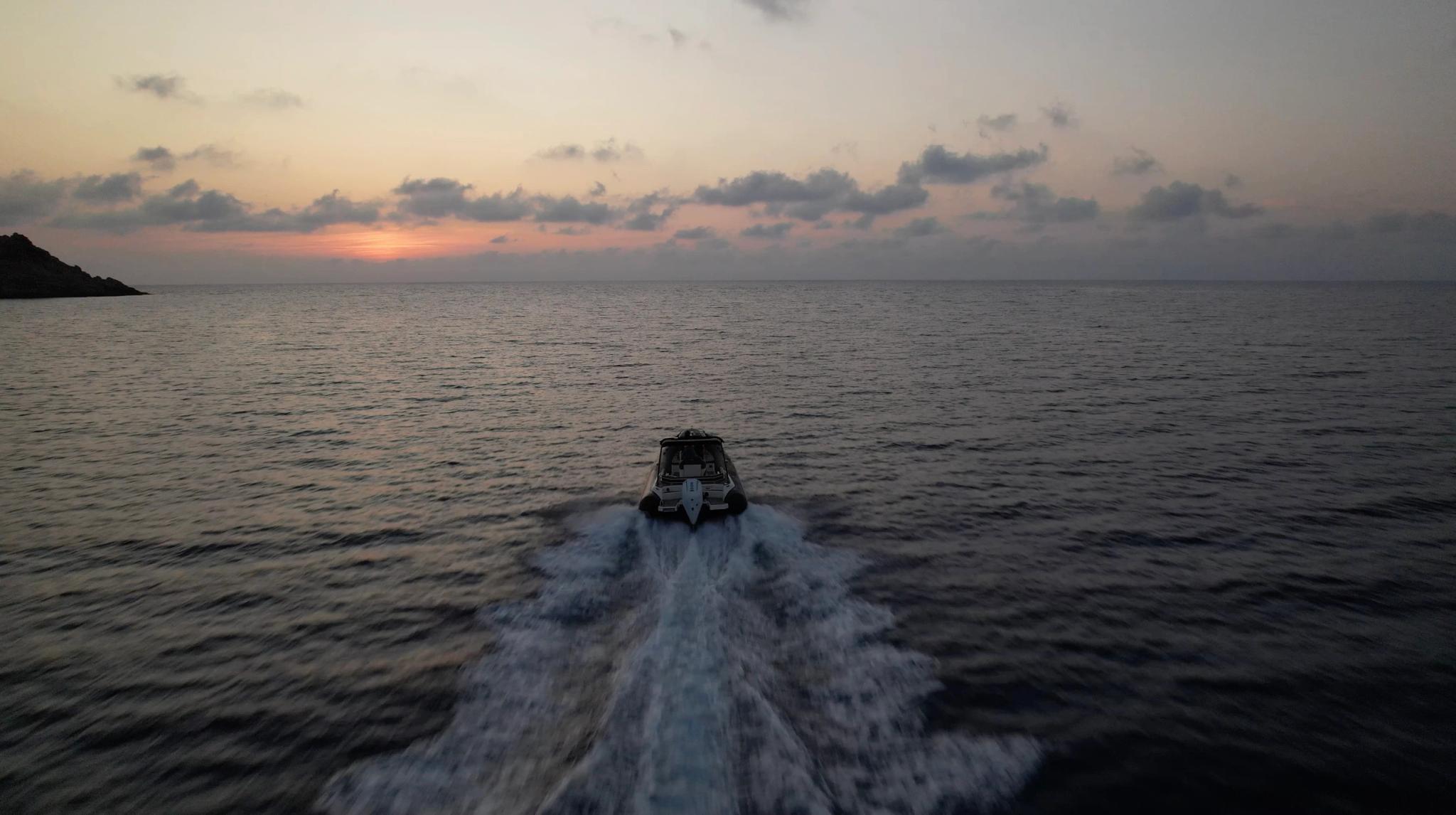 Un bateau de plaisance navigue au coucher de soleil près d'Île-Rousse, symbolisant la vente de bateaux de plaisance dans cett