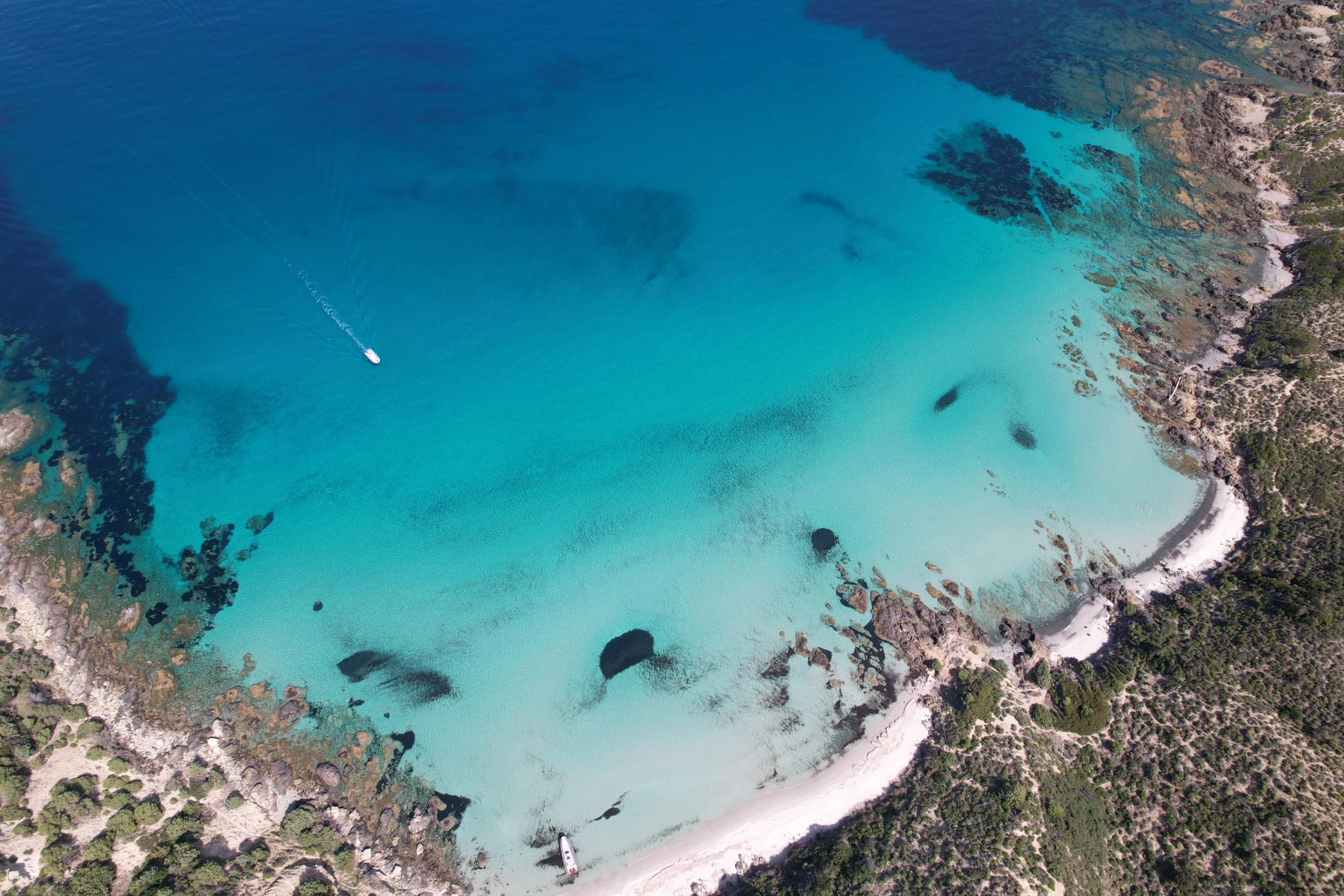 Vue aérienne d'une baie turquoise avec bateau à Île-Rousse en Corse