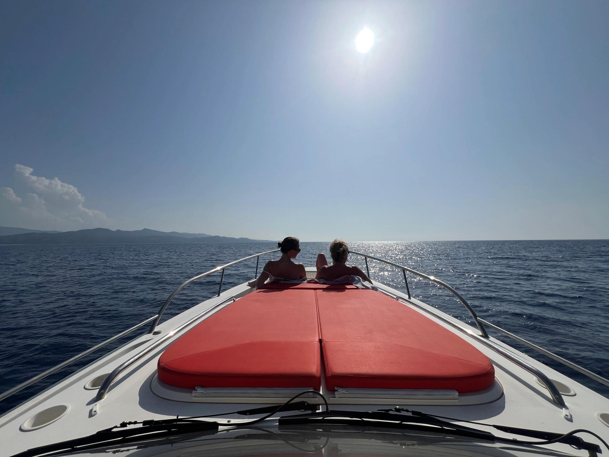 Deux personnes sur un bateau à moteur avec coussins rouges naviguant près d'Île-Rousse